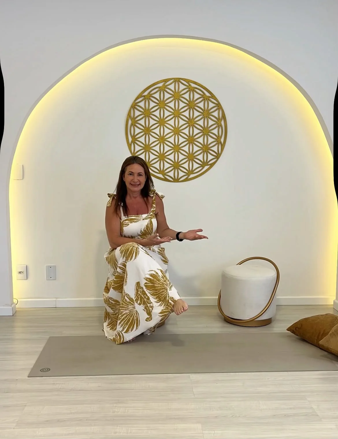 Sílvia Martins sentada diante do nicho em arco iluminado da sala dos encontros